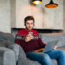 a girl sitting on a couch and using internet on his phone